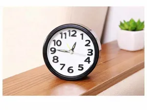 Macro view of the 3D numerals and luminous hands on a round black alarm clock