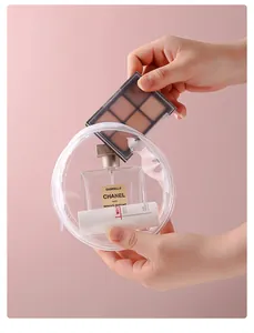 Nahaufnahme einer PVC-Tasche, die mit einer Make-up-Palette und Parfum gefüllt wird