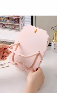 Verstelbare verborgen standaard aan de achterkant van de roze cartoon schaap make-up spiegel.
