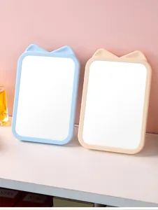 Detail of cute cat ear shaped desktop makeup mirrors in blue and peach colors.