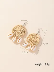 Detailed view of handmade round rattan earrings with three natural shell charms