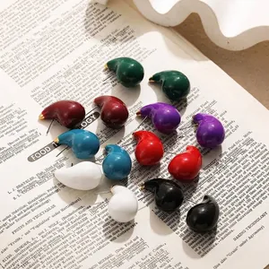 Vue macro de boucles d'oreilles gouttes en émail coloré sur fond de livre ancien