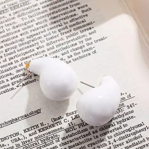 Vue détaillée en gros plan de boucles d'oreilles en émail blanc sur une page de livre ancien.