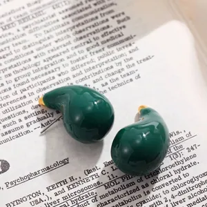 Gros plan de boucles d'oreilles clous en émail vert foncé brillant en forme de goutte.