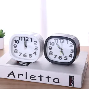 Minimalist rectangular alarm clocks in black and white styles on a wooden desk.
