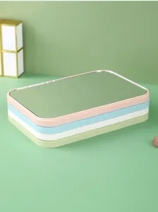 Detail showing four stacked portable makeup mirrors in pastel pink, blue, white, and green.