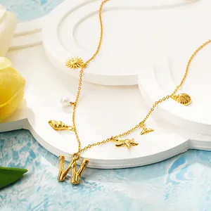 Primo piano di una collana in oro 18 carati con ciondoli a tema spiaggia e lettera W.