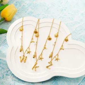 Dettaglio di collane con lettere in oro 18K e ciondoli marini come conchiglie e stelle.