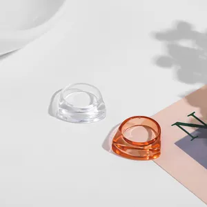 Detailed view of clear and amber chunky acrylic rings on a minimalist white surface
