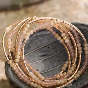 Macro view of multi-layered beaded bracelet with rose gold metallic accents and peach crystals