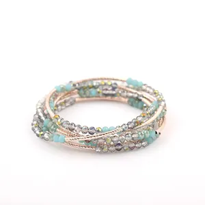 Detailed view of multi-layered turquoise and crystal beaded bracelet with rose gold coils