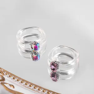 Close-up detail view of two trendy acrylic rings with colorful square gemstones.