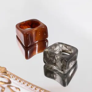 Macro view of chunky amber and marble grey acrylic square rings with reflection