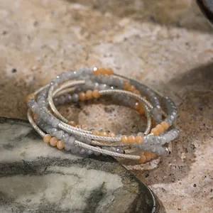 Detailed macro shot of a multilayered beaded bracelet with gray and orange crystals