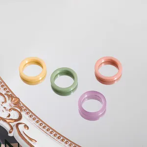 Close-up of four colorful pastel acrylic rings on a reflective mirror surface
