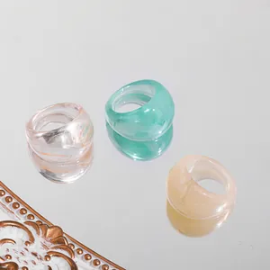 Macro detail showing three chunky colorful acrylic rings on a reflective mirror surface