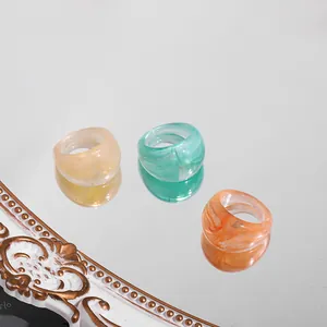 Detail view of a colorful chunky acrylic ring set placed on a reflective mirror