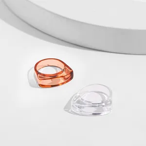 Close-up of modern amber and clear acrylic rings with asymmetric geometric design