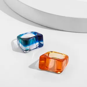 Detail view of colorful square acrylic rings with glossy finish on white surface