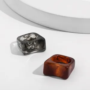 Detailed macro shot of two thick square acrylic rings with grey marble and amber textures