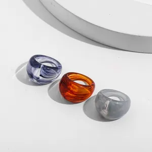 Detail shot of three colorful marbled acrylic resin rings set in a minimalist studio style
