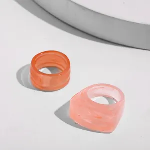 Close-up detail of a trendy marbled acrylic ring set in orange and light pink colors