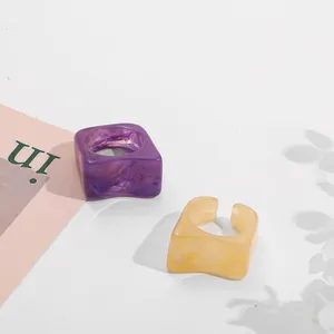 Detailed view of purple and amber acrylic rings with marble texture set on white surface