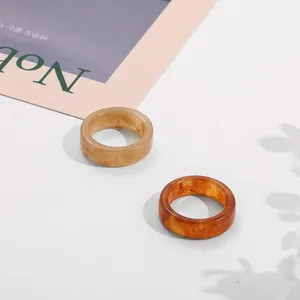 Detailed macro view of two amber acrylic rings with unique marble textures on white background
