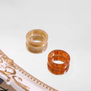 Close-up of trendy acrylic resin rings with amber and beige marble texture patterns