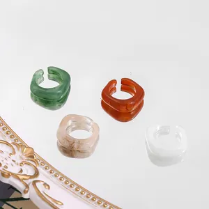 Set of four trendy acrylic rings in various colors on a reflective mirror surface