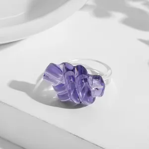 Close-up detail showing the twisted knot design of a purple acrylic ring in natural light