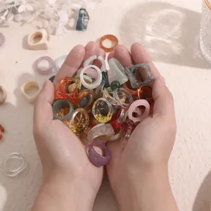Assorted colorful acrylic resin ring set held in hands for trendy fashion display