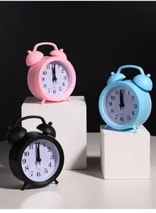 Close-up of minimalist silent bedside quartz alarm clocks in pink, blue, and black colors
