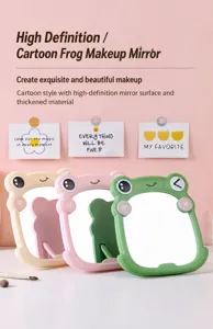 Close-up of three colorful cartoon frog makeup mirrors with portable folding stands.