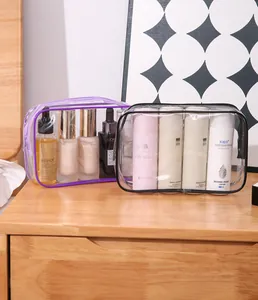 Transparent PVC travel cosmetic bags with purple and black zippers on a wooden table.