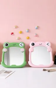 Close-up detail of cute frog-shaped plastic makeup mirrors in green and pink finishes