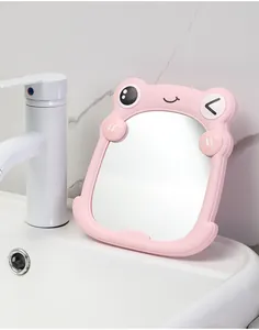 Close-up of cute pink frog cartoon makeup mirror placed on a white bathroom sink