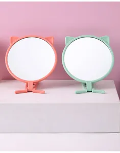 Vorderansicht von rosa und grünen Katzenohr-Make-up-Spiegeln mit Klappständer auf Podest