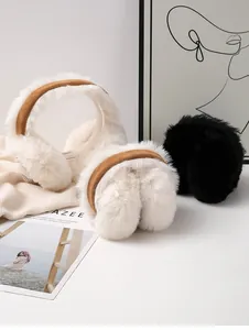 Close-up detail of plush winter earmuffs in soft white and classic black faux fur material