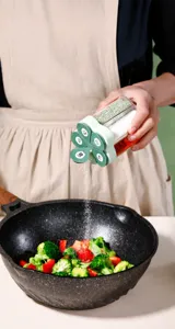 Gros plan d'un pot à épices 4 en 1 pratique versant des assaisonnements dans une poêle chaude