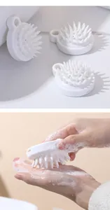 Detail showing a hand using the white silicone scalp massage brush with rich soapy lather.