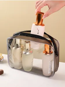 Große transparente PVC-Kulturtasche, die mit verschiedenen Hautpflegeprodukten gefüllt wird