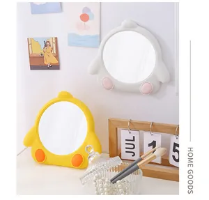 Close-up view of cute yellow and white chicken-shaped mirrors in a cozy desk setting