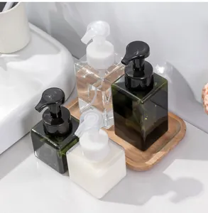 Four square mousse foam pump bottles in various sizes and colors on a wooden tray