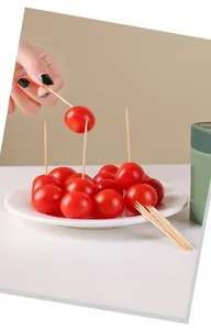 Close-up detail of bamboo toothpicks used for serving fresh cherry tomatoes on a white plate