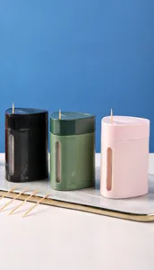 Three colors of automatic push-type toothpick boxes displayed on a tray for home decor.