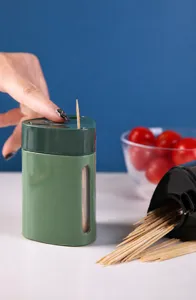 Close-up of a green automatic toothpick dispenser being pressed to pop out a toothpick