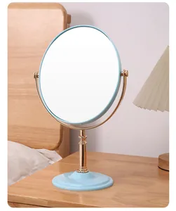 Detail view of a vintage-style blue and gold double-sided makeup mirror on a bedside table.