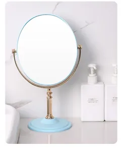 Elegant round desktop makeup mirror with light blue base and gold rotating stand.
