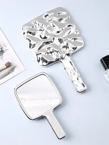 Vista dettagliata di uno specchio per trucco argento con retro con texture a onde d'acqua